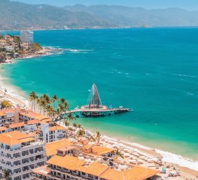 Vista encantadora de Puerto Vallarta, México. Bahías pintorescas, playas de arena dorada, montañas verdes y la arquitectura tradicional mexicana se combinan para crear la atmósfera única de este destino. Descubre la belleza y el encanto de Puerto Vallarta en tu próxima escapada.
