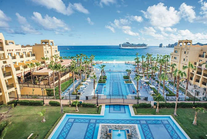 Vista impresionante del Hotel Riu Santa Fe en Los Cabos, México. Disfruta de unas vacaciones inolvidables en este resort todo incluido, con su arquitectura moderna, piscinas magníficas, restaurantes temáticos y acceso directo a las playas doradas de Baja California Sur. Vive la experiencia de lujo y entretenimiento que ofrece el Riu Santa Fe en tu escapada a Los Cabos.